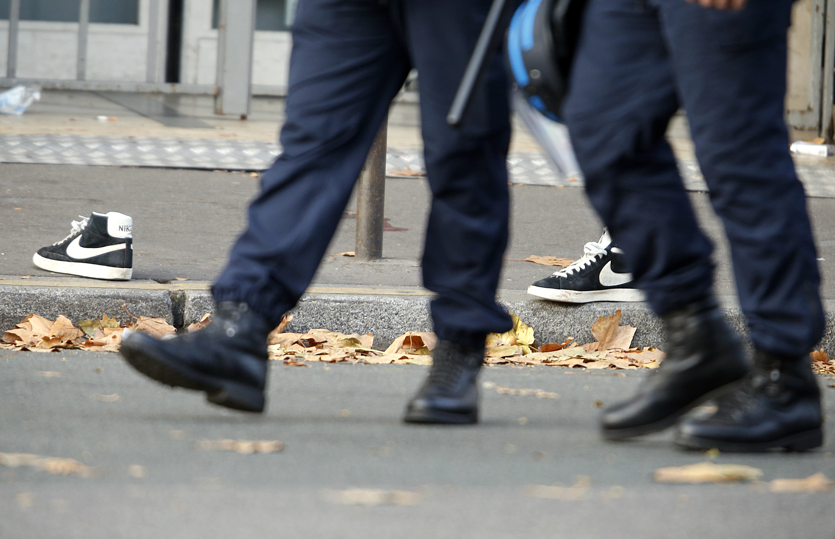 La POlicía pasa al lado de un par de zapatillas abandonadas en una de las zonas de los ataques de París.      REUTERS/Charles Platiau - RTS6Y5C