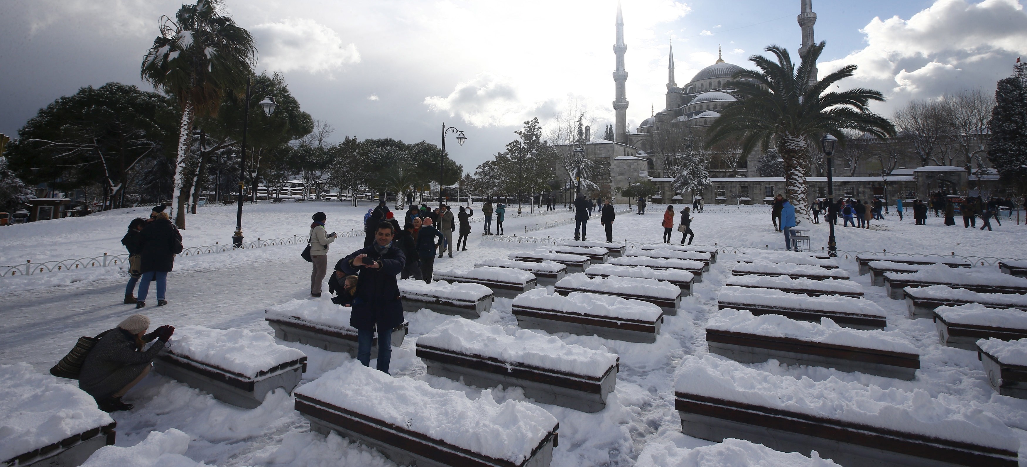 Tourists take a photo on the snow-covered Sultanahmet Square in the historic old town of Istanbul, Turkey,  December 31, 2015.  REUTERS/Osman Orsal - RTX20MLP