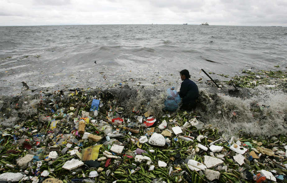 A man collects recyclable plastic materials, washed ashore by waves, which will be sold for 21 pesos ($0.48) in exchange for food in Manila  August 2, 2008. REUTERS/Cheryl Ravelo (PHILIPPINES) - RTR20K6N