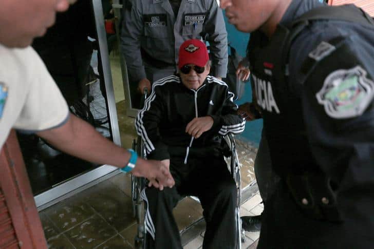 Former Panamanian dictator Manuel Noriega sits in a wheelchair as prison wardens help him after a health check up at the facilities of the Public Ministry in Panama City, Panama, July 22, 2016. REUTERS/Alberto Solis/Files