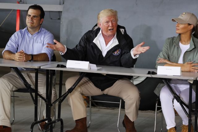 El presidente de los Estados Unidos, Donald Trump, se encuentra entre el gobernador de Puerto Rico, Ricardo Rosselló, y la primera dama, Melania Trump, mientras recibe una información sobre los daños causados ​​por huracanes en la base de la Guardia Nacional Aérea Muniz. (Reuters / Jonathan Ernst)