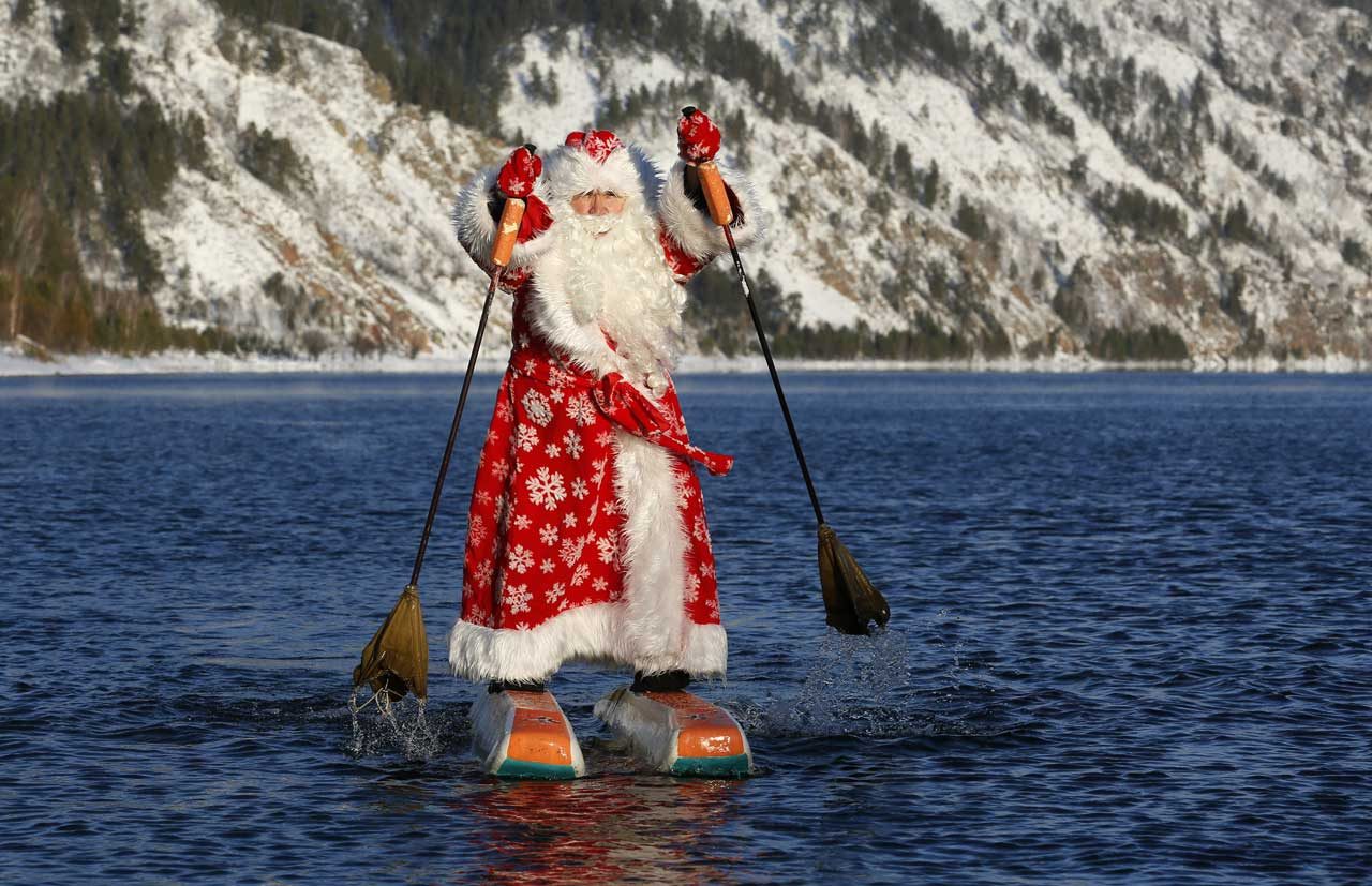 Nikolai Vasilyev, de 64 años, disfrazado de Padre Frost, el equivalente ruso de Santa Claus, con esquís acuáticos a lo largo del río Yenisei en Rusia. REUTERS
