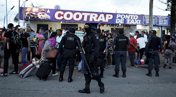 Policías antidisturbios conversan con venezolanos después de revisar sus pasaportes o documentos de identificación en el punto de control Pacaraima, estado de Roraima, en Brasil (Reuters)