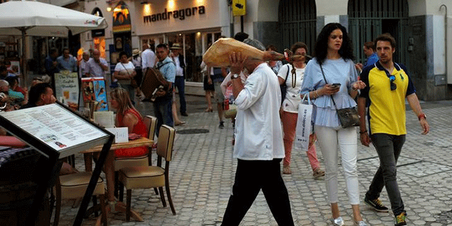 Un camarero lleva un jamón en una terraza de un resturante en el centro de Málaga, el 7 de junio de 2018. REUTERS/Jon Nazca