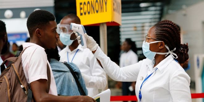 Una trabajadora de la salud chequea la temperatura de un viajero en el aeropuerto internacional de Kotoka en Accra, Ghana, como parte de las medidas para evitar la propagación del coronavirus