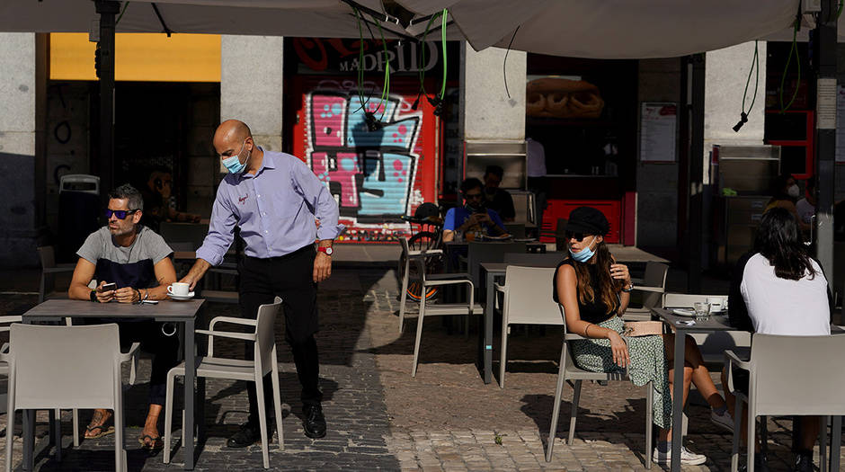 Un camarero que usa una máscara facial protectora sirve una bebida para un cliente en una sección de un restaurante al aire libre que reabrió por primera vez en más de 2 meses en medio del brote de la enfermedad por coronavirus (COVID-19), en la Plaza Mayor de Madrid, España, 25 de mayo de 2020. REUTERS / Juan Medina