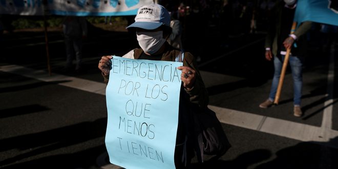 Un manifestante con una máscara facial sostiene un cartel que dice "emergencia para los que menos tienen", durante una protesta para exigir recursos para los vulnerables, en medio de la enfermedad por coronavirus (COVID-19), en Buenos Aires, Argentina, el 11 de junio de 2020. REUTERS / Agustin Marcarian / Foto de archivo