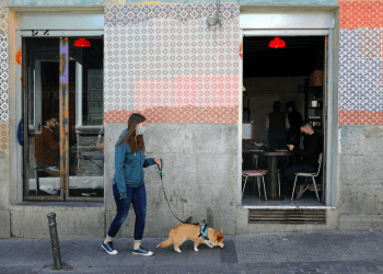 Mujer con un perro pasa junto a la gente dentro de un bar en el centro de Madrid.