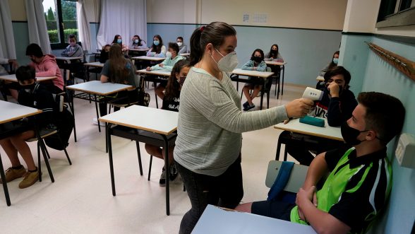 Una profesora utiliza un termómetro digital para medir la temperatura de los estudiantes en la primera semana de clases después de las vacaciones de verano durante el brote de la enfermedad por coronavirus (COVID-19), en Munguia, España./REUTERS/ Vincent West