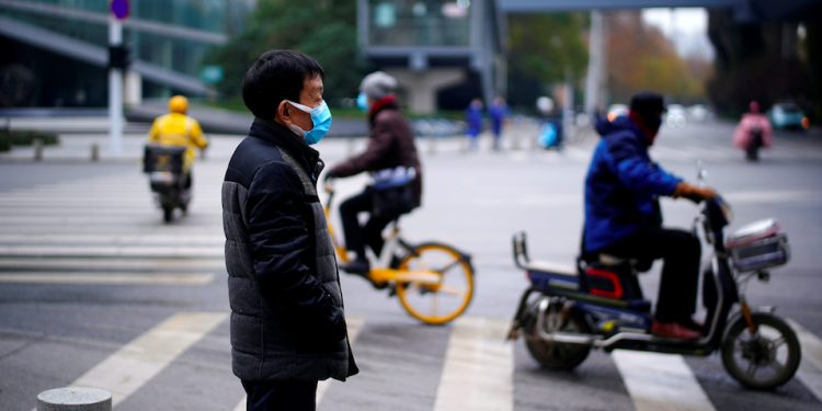 Hombre con una máscara parado cerca de una calle, casi un año después del inicio del brote de la enfermedad por coronavirus (COVID-19), en Wuhan, Hubei