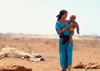 UNICEF/Oloo Una madre con su hijo en brazos caminado junto a los cadáveres del ganado muerto a causa de la grave sequía en Marsabit, en Kenya.